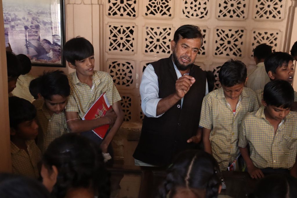 teacher standing among young boys in shirts